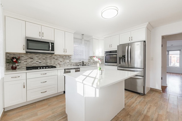 kitchen featuring sink, a kitchen island, tasteful backsplash, white cabinets, and appliances with stainless steel finishes