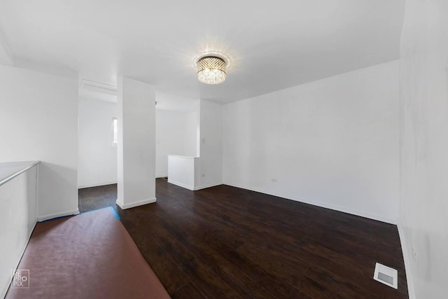 unfurnished room featuring a chandelier and dark hardwood / wood-style flooring