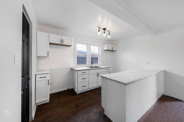 kitchen featuring white cabinets, sink, beamed ceiling, and dark wood-type flooring