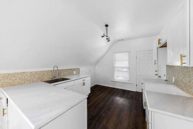 kitchen featuring lofted ceiling, sink, dark hardwood / wood-style floors, tasteful backsplash, and white cabinetry