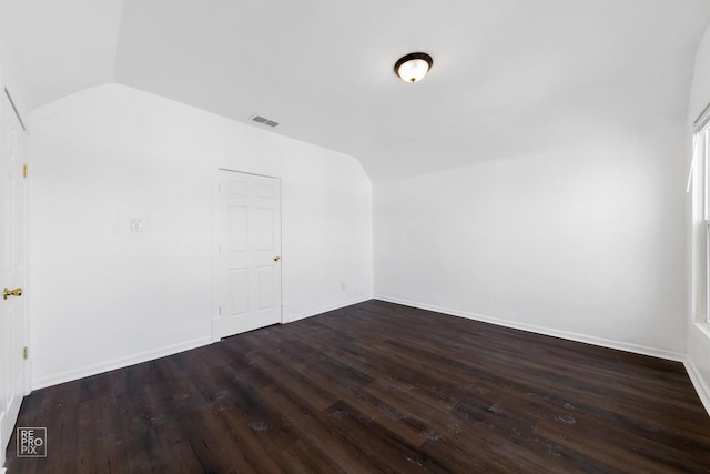 spare room with lofted ceiling and dark wood-type flooring