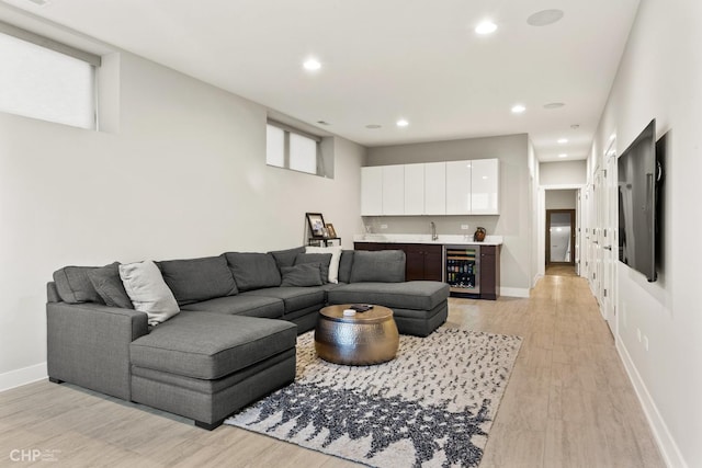 living room with light hardwood / wood-style floors, beverage cooler, and sink