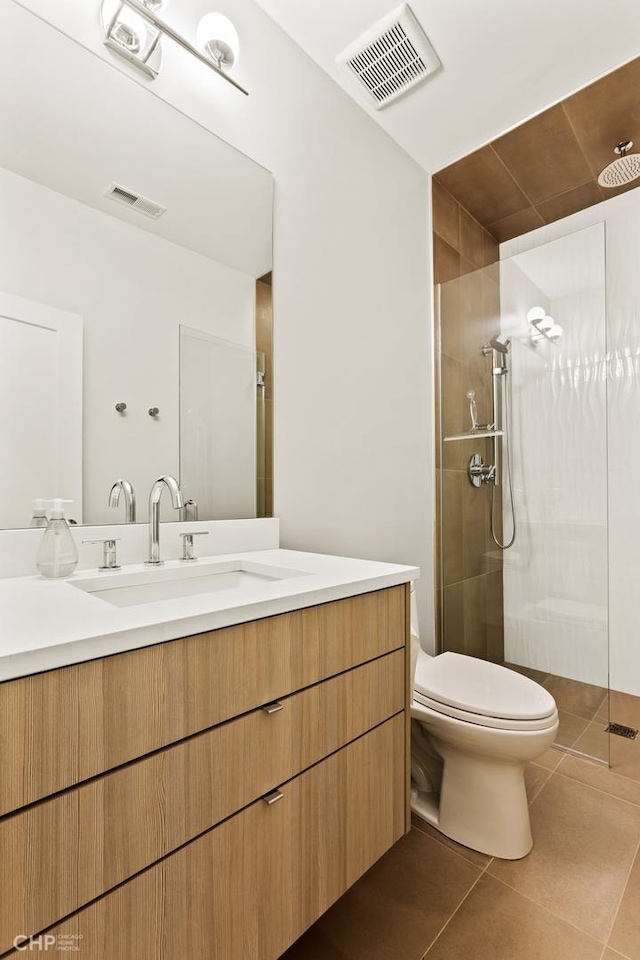 bathroom with tile patterned floors, vanity, toilet, and a shower with shower door