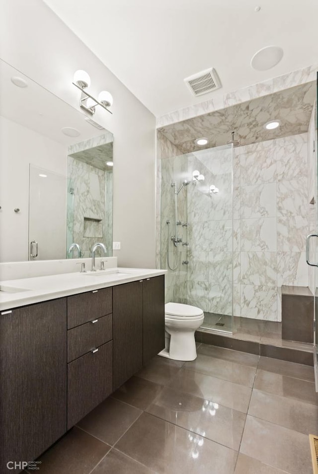 bathroom with tile patterned floors, vanity, toilet, and a shower with shower door