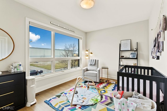 bedroom with light hardwood / wood-style floors and a crib