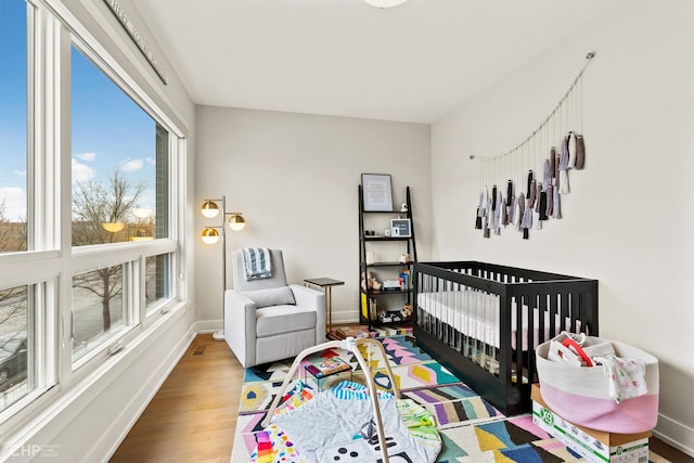 bedroom with a nursery area and hardwood / wood-style flooring