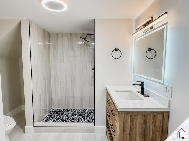 bathroom with vanity, toilet, and a tile shower