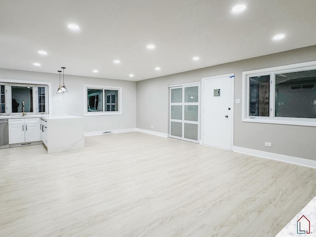 unfurnished living room featuring sink and light hardwood / wood-style floors