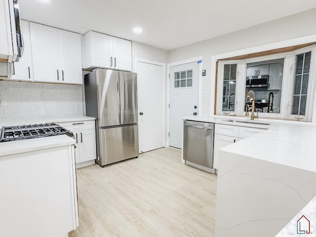 kitchen featuring white cabinets, light stone counters, stainless steel appliances, and tasteful backsplash