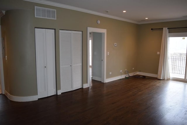 unfurnished bedroom with access to outside, dark hardwood / wood-style flooring, two closets, and ornamental molding