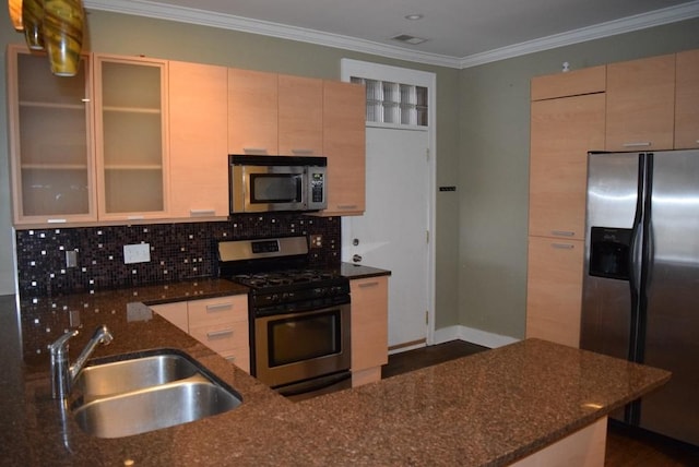 kitchen with appliances with stainless steel finishes, dark stone counters, crown molding, sink, and light brown cabinets