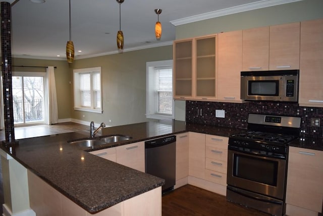 kitchen with sink, hanging light fixtures, stainless steel appliances, dark stone counters, and ornamental molding