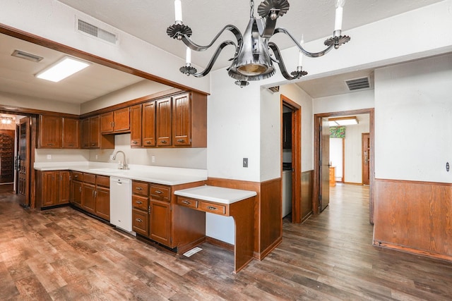 kitchen with white dishwasher, dark hardwood / wood-style floors, sink, and wooden walls