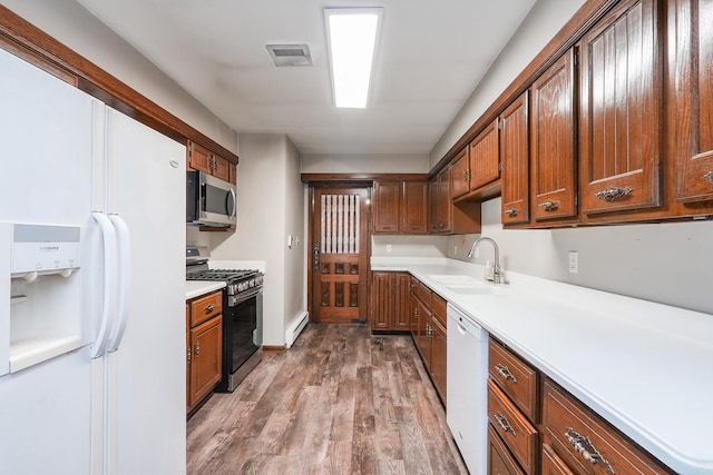 kitchen with baseboard heating, wood-type flooring, sink, and appliances with stainless steel finishes