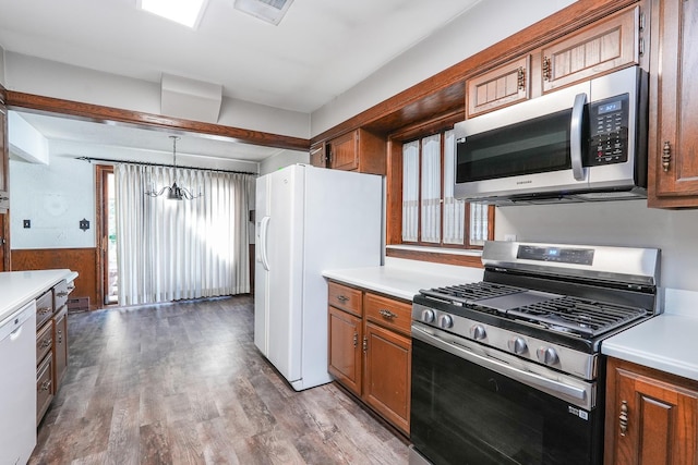 kitchen with stainless steel appliances, an inviting chandelier, hardwood / wood-style floors, pendant lighting, and wooden walls