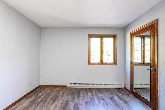 empty room with dark hardwood / wood-style flooring, a textured ceiling, and a baseboard heating unit