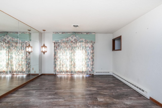 empty room with dark hardwood / wood-style flooring, a baseboard radiator, and plenty of natural light