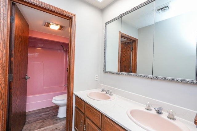 full bathroom featuring washtub / shower combination, vanity, wood-type flooring, and toilet