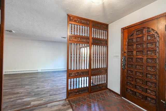 foyer with dark wood-type flooring, a textured ceiling, and a baseboard heating unit