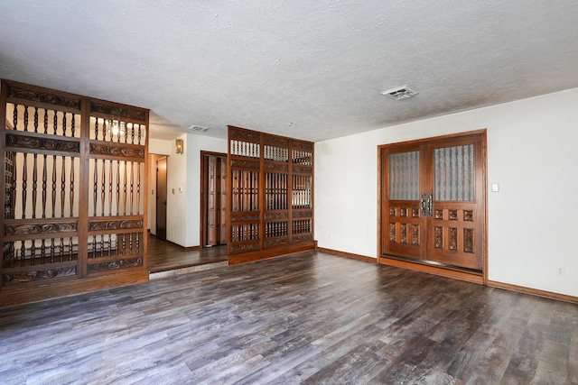 unfurnished living room featuring a textured ceiling, french doors, and dark hardwood / wood-style floors