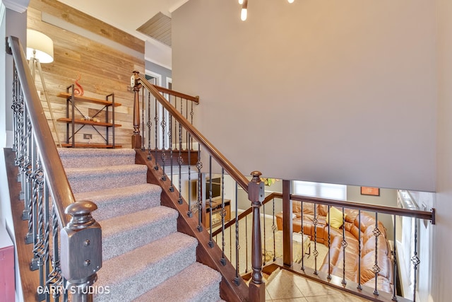 stairs with tile patterned floors and wood walls