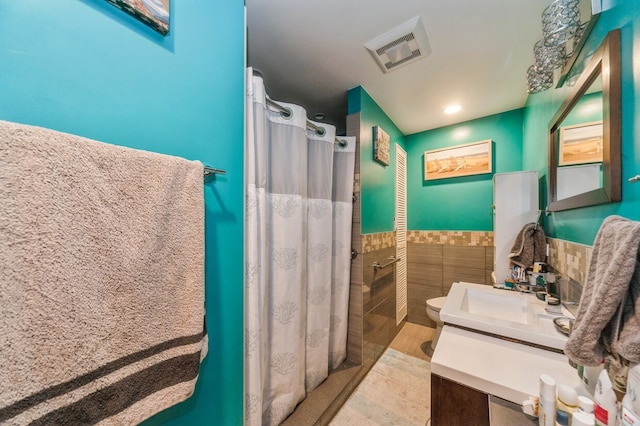 bathroom featuring a shower with curtain, vanity, toilet, and tile walls