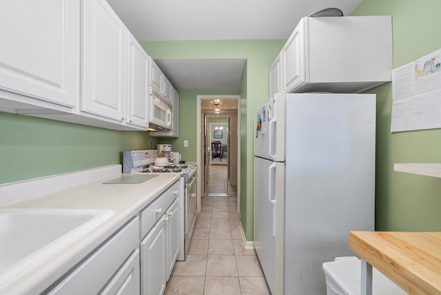 kitchen featuring light tile patterned floors, white cabinets, white appliances, and sink