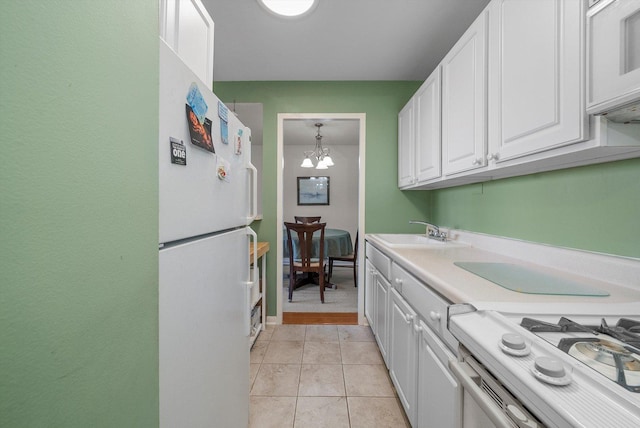 kitchen featuring sink, a notable chandelier, pendant lighting, white appliances, and white cabinets