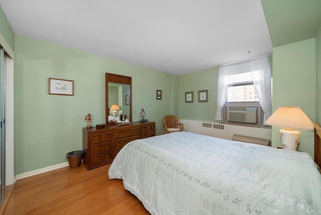 bedroom with light hardwood / wood-style floors, radiator, and cooling unit