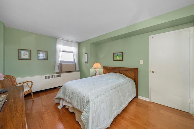 bedroom with radiator heating unit and light wood-type flooring