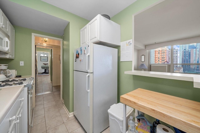 kitchen featuring white cabinets, light tile patterned flooring, and white appliances