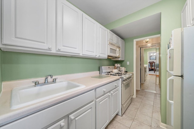 kitchen featuring white cabinets, white appliances, light tile patterned flooring, and sink