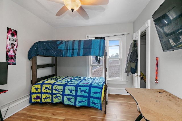 bedroom with multiple windows, ceiling fan, and hardwood / wood-style flooring