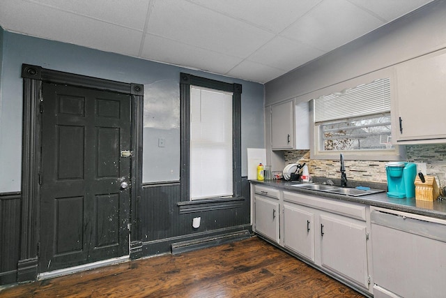 kitchen featuring white cabinets, a drop ceiling, dark wood-type flooring, sink, and dishwasher