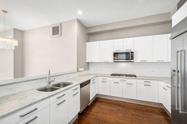 kitchen with pendant lighting, sink, appliances with stainless steel finishes, tasteful backsplash, and white cabinetry