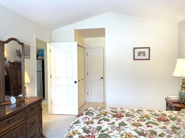 carpeted bedroom featuring stainless steel refrigerator, vaulted ceiling, and a closet