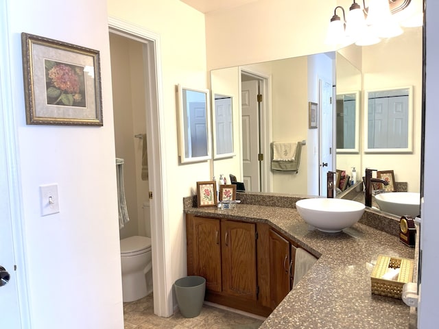 bathroom with an inviting chandelier, vanity, and toilet