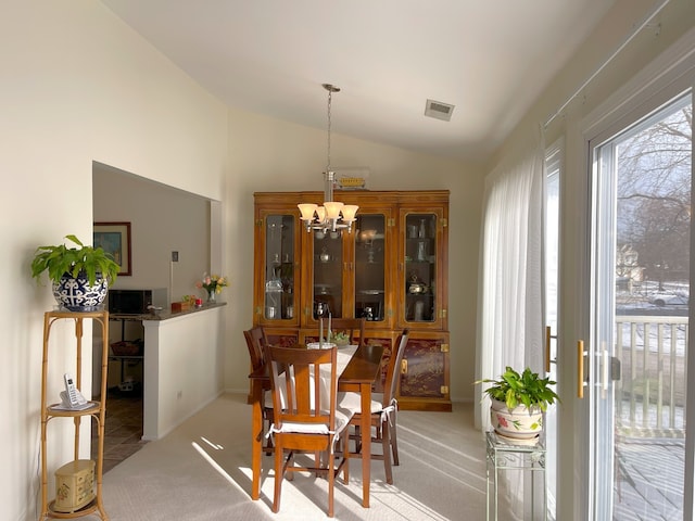 dining area with lofted ceiling, light carpet, and a chandelier