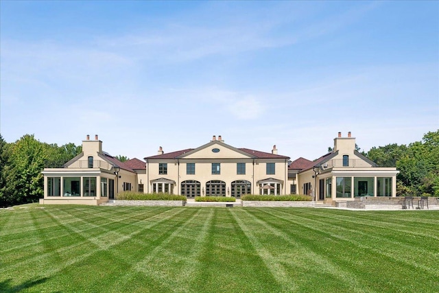 back of property with a lawn and a sunroom