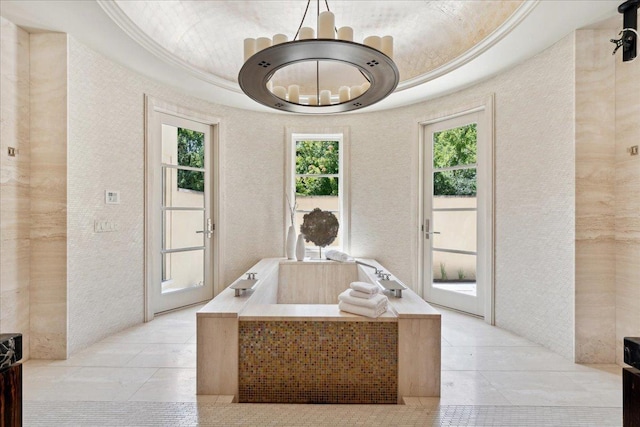 bathroom with a tray ceiling, a bathing tub, a healthy amount of sunlight, and ornamental molding