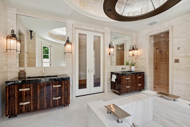 bathroom with french doors, vanity, tile walls, and walk in shower