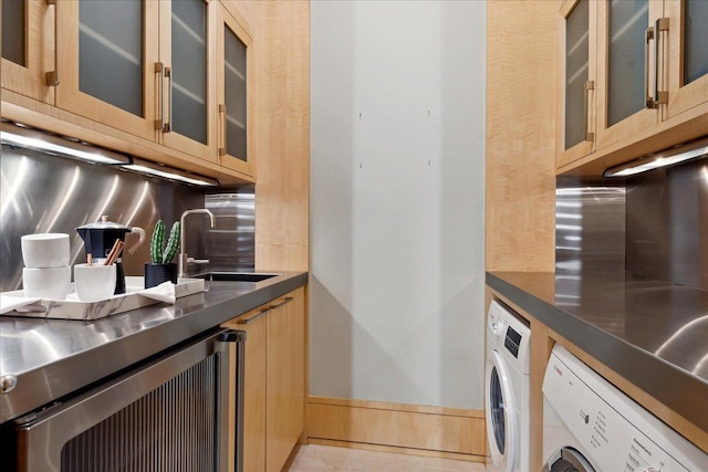 kitchen with backsplash, wine cooler, sink, and washer / dryer