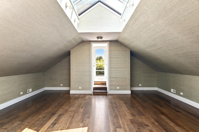 additional living space featuring vaulted ceiling with skylight and dark wood-type flooring