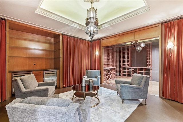 sitting room with wooden walls, ornamental molding, wine cooler, and a tray ceiling