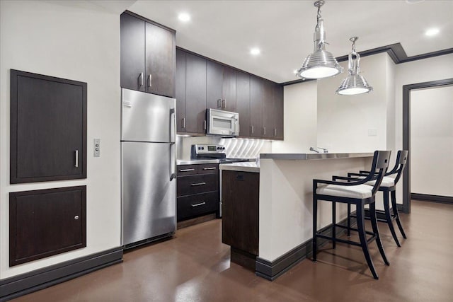 kitchen featuring pendant lighting, a kitchen breakfast bar, crown molding, appliances with stainless steel finishes, and kitchen peninsula