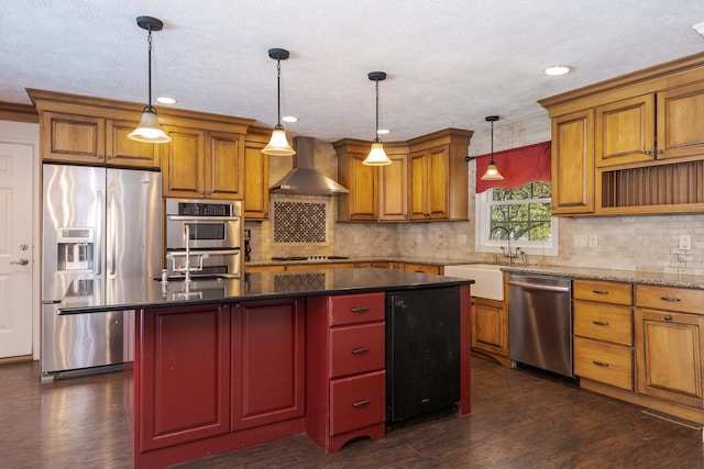 kitchen with a center island, wall chimney range hood, stainless steel appliances, and hanging light fixtures