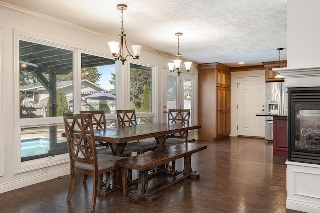 dining space with dark wood-type flooring, ornamental molding, a textured ceiling, and a notable chandelier