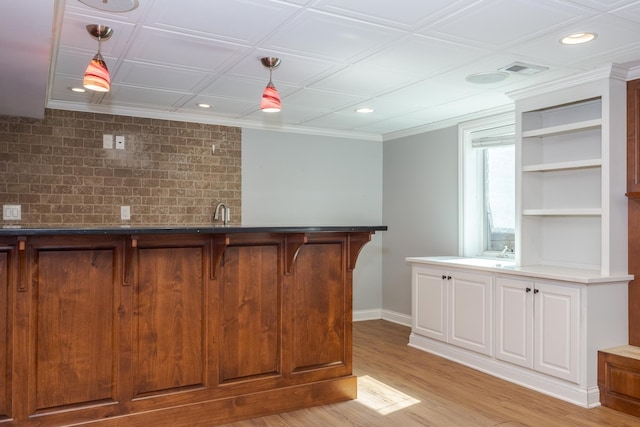 bar with built in shelves, sink, light hardwood / wood-style floors, white cabinetry, and hanging light fixtures