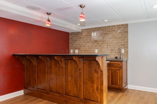 bar with decorative light fixtures, light hardwood / wood-style flooring, and sink