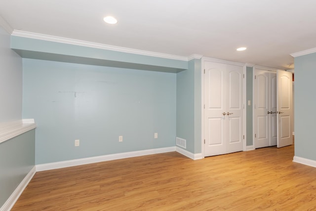 basement featuring crown molding and light hardwood / wood-style floors